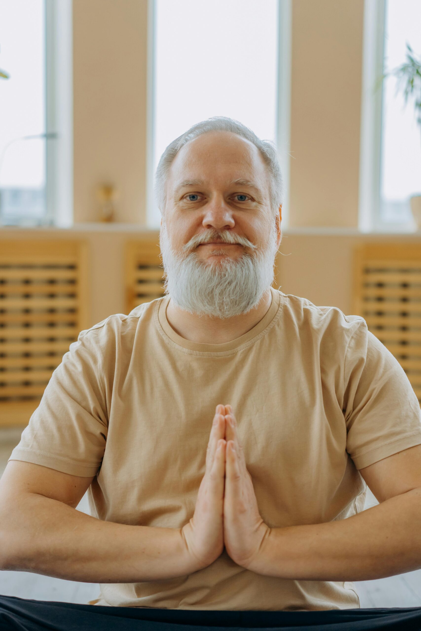 A senior man exudes calmness and focus while meditating indoors, symbolizing wellness and positive aging.